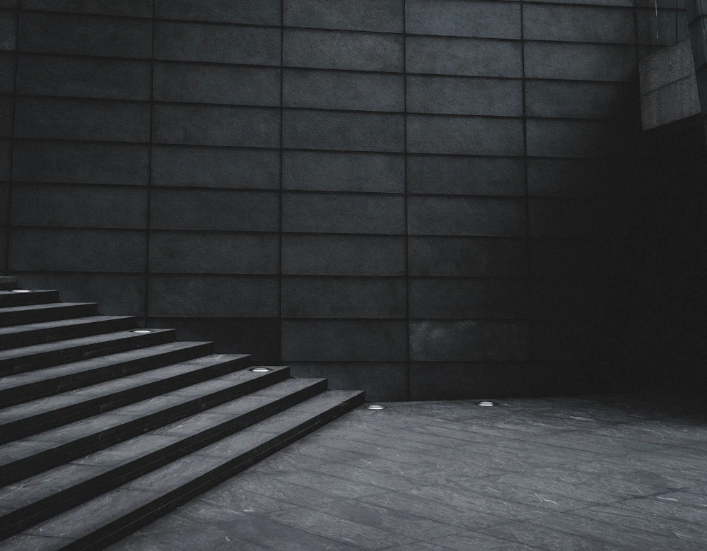 A dark cast-concrete stairwell lit from below, standing in for a private entrance.